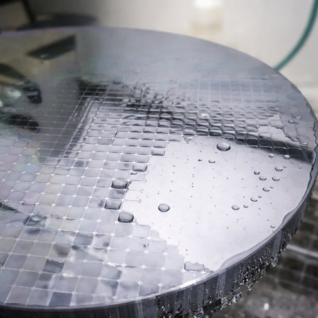 Surface condition of precision metal wafer after industrial cleaning, showing uniform water film and droplets.png