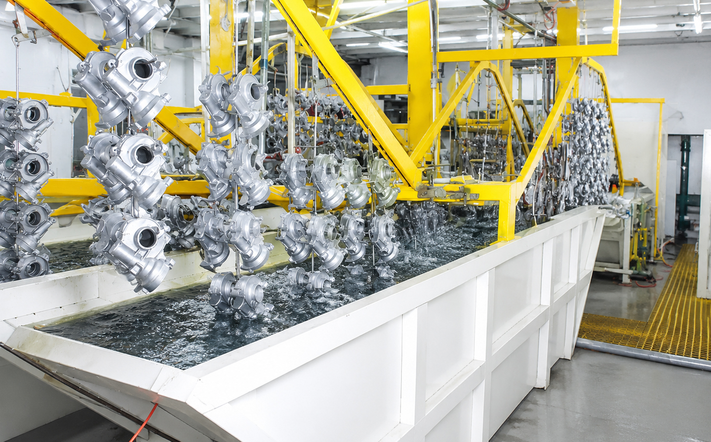 Bright-industrial-immersion-cleaning-line-with-metal-parts-suspended-above-a-chemical-cleaning-tank-inside-a-modern-factory-workshop
